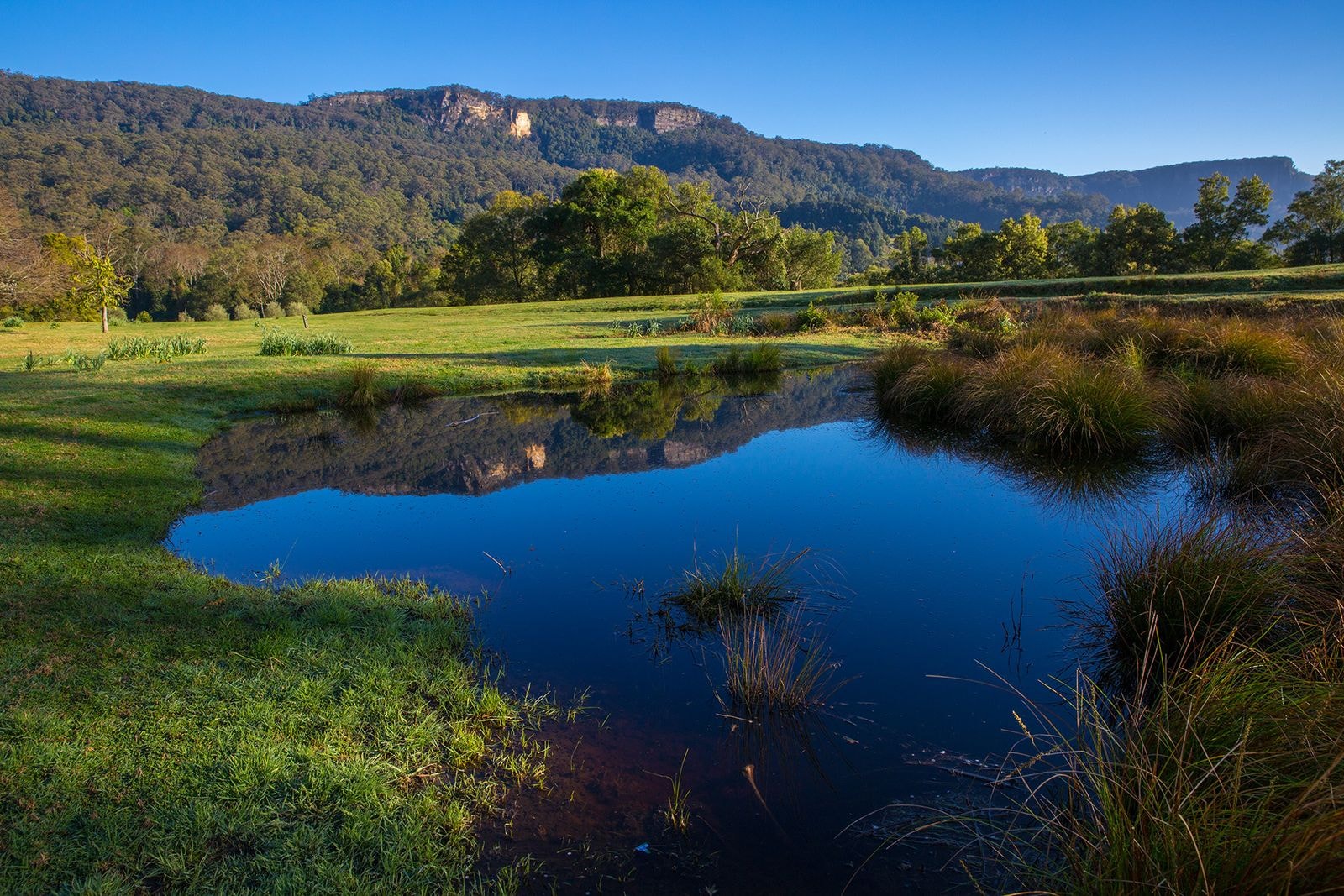 A still lake below the sandstone escarpment at sunset
