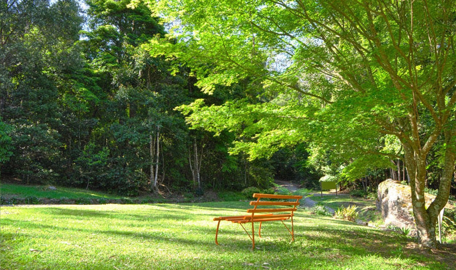 A bench beneath established trees in the retreat gardens